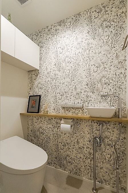 廊下からアクセスできるトイレは植物モチーフの壁紙がアクセントに。手洗い器付きです。