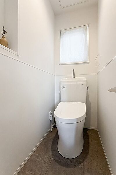 トイレは、白を基調にしたシンプルな設え。腰壁には、洗面スペース同様キッチンパネルが採用されています。