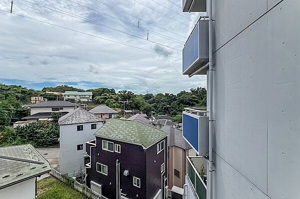 高台ならではの、周囲の緑や住宅街を見渡す景色。マンションが雁行した形状のため、右手には隣接する住戸の壁があります。