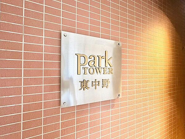 「Park TOWER 東中野」の看板が、洗練されたデザインで住まいの顔を飾ります。温かみのあるレンガ調の外壁が、家族の毎日を優しく包み込む上質な暮らしを予感させます。