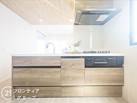 木目調のパネルが温かみを添えるキッチンは、インテリアの一部として美しく空間に溶け込みます。使い勝手を考慮した広いワークトップが、日々の料理時間をよりクリエイティブなひとときに変えてくれます