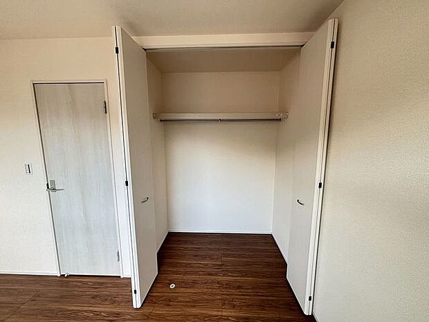 開口部が広い折れ戸が採用されたクローゼットです。内部にはハンガーパイプと枕棚が備わっており、衣類の吊り下げや上部の空間を活用した整理に対応します。