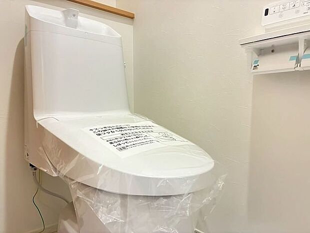 白を基調とした清潔感あふれるトイレスペースです。寒い季節も快適に過ごせる温水洗浄便座を完備。小物が置けるカウンター付きの2連ペーパーホルダーや手洗い付きタンクなど、使いやすさに配慮された設計です