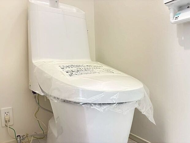白を基調とした清潔感あふれるトイレスペースです。快適にご使用いただける温水洗浄便座や、便利な手洗い付きのタンクを完備。無駄のないシンプルなデザインで、毎日のお手入れもスムーズに行える設計です。