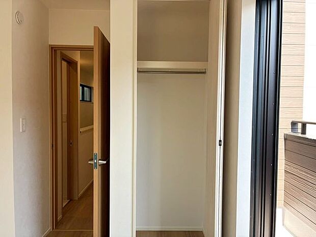 衣類をすっきりと掛けられるハンガーパイプと、上部に便利な枕棚が付いたクローゼットを備えています。バルコニーに面した窓から自然光が差し込む明るい空間で、木の温もりを感じるナチュラルな内装も魅力です。
