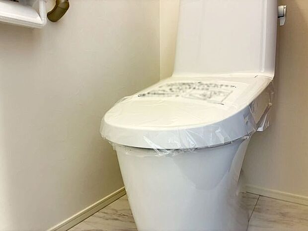 白を基調とした、明るく清潔感のあるトイレスペースです。冷え込む季節も快適にご利用いただける温水洗浄便座を備えています。床面はお手入れがしやすい素材を採用し、毎日のお掃除の負担を軽減できる設計です。