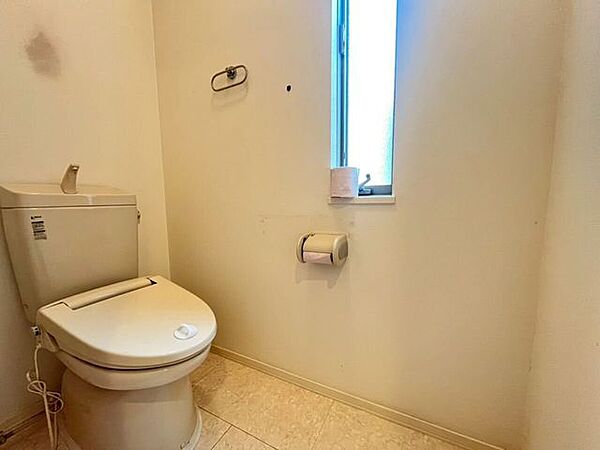2階トイレ便器には手洗い機能付きタンクが採用されています。壁面にはペーパーホルダーやタオル掛けのほか、採光や換気に利用できる窓が配置されています。