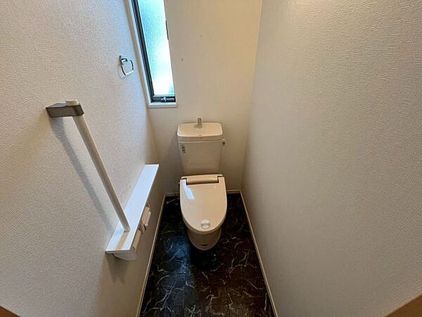 1階トイレ壁面には立ち座りを補助する手すりと、小物を置けるカウンター付きのペーパーホルダーが設置されています。採光や換気に利用できる窓も配置されています。