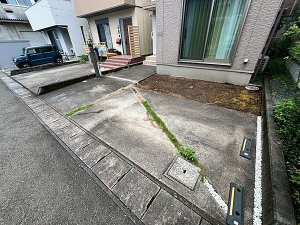 建物の前面にはコンクリート舗装の駐車スペースが設けられています。駐車位置の目安となる車止めが設置されています。