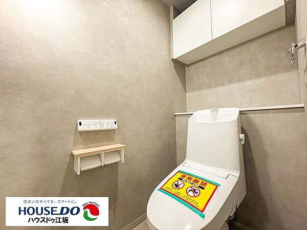 落ち着いたグレー基調クロスがシックな印象を与えるレストルーム。快適な温水洗浄便座を装備し、上部にはトイレットペーパーなどを隠してしまえる扉付き吊戸棚を完備。清潔感と使い勝手を備えた空間です。