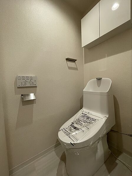温水洗浄便座を完備した、清潔感のあるトイレ空間です。上部には扉付きの吊戸棚があり、トイレットペーパーのストックや掃除用品を人目を気にせず収納できます。毎日使う場所だからこそ、快適さにこだわりました!