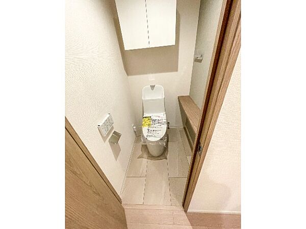 白を基調とした清潔感のある空間に、温水洗浄便座が備わったトイレです！トイレットペーパーなどを隠して収納できる吊戸棚のほか、ちょっとした小物を飾れるカウンターも付いており、好みの空間に演出できます♪
