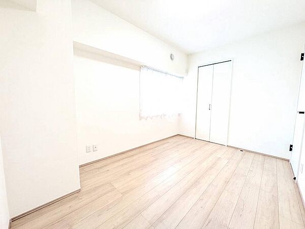 大きな窓から自然光がたっぷり差し込む、明るく心地よい洋室。白壁と木目フローリングが調和し、インテリアの自由度も高い空間です。
