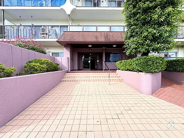 整備された植栽とタイル敷きの広いアプローチが迎えるエントランス。落ち着いた色合いの外観が、日常の帰宅シーンに安らぎと品格をもたらす佇まいです。
