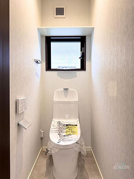ワイトで統一された清潔感あふれるトイレ空間。温水洗浄便座一体型の便器を採用し、小窓から自然光が差し込む明るく快適な雰囲気です。