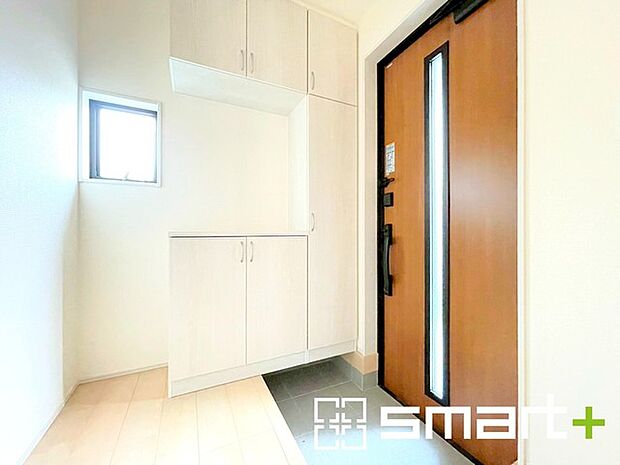 ~圧迫感のない明るい玄関~ ・窓に加えて玄関ドアのガラス部分からも穏やかな陽が入り、明るい玄関になります。 ・飾り棚としても演出できるコの字型の下駄箱は大容量の収納力。