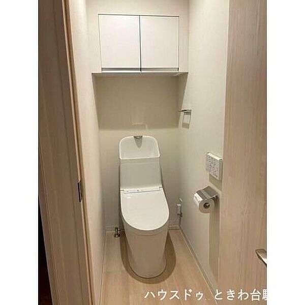 スッキリとしたデザインの温水洗浄便座付きトイレ。上部には吊戸棚が設置されており、トイレットペーパーなどのストックを人目につかず収納できるため、常に清潔で整った空間を維持できます。