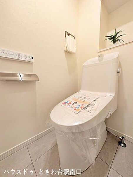 清潔感のある温水洗浄便座付きのトイレです。上部には吊戸棚を備えており、トイレットペーパーなどのストックもスマートに収納できます。