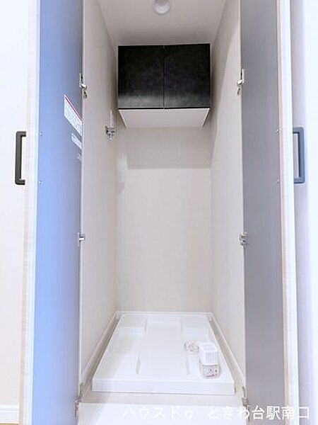 新規設置された洗濯機パン。上部には洗剤や洗濯ネットなどのストックに役立つ扉付きの吊戸棚を設置しています。