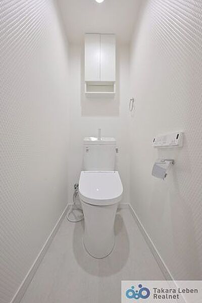 白を基調とした清潔感のあるトイレ。上部に収納もついておりますので、とても便利です。