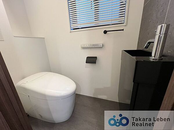 手洗い場付きタンクレストイレ。温水洗浄リモコンは操作のしやすい壁掛けタイプです。