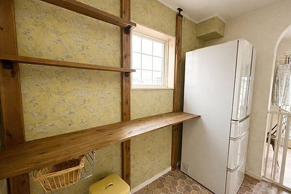 キッチンの背面には、ストック品や家電をまとめて収納できる使い勝手の良い空間です。温かみのあるクロスで、家事時間が心地よくなるスペースです。※AI加工を施しています。