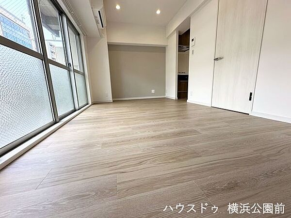 エアコン完備で引越し当日から快適。バルコニーへ繋がる大きな窓から光が入ります。奥のキッチンへ遮るものなく移動でき、一面の壁にはアクセントクロスを採用しています。