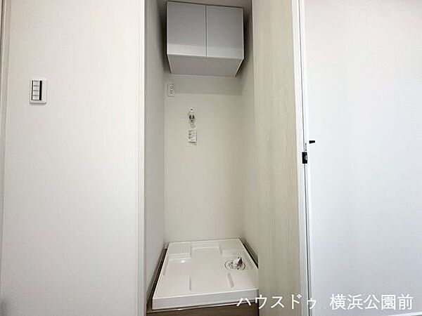 上部に便利な扉付きの吊戸棚が備わった洗濯機置き場です。洗剤や日用品のストックを手の届く位置に収納可能。限られたスペースを有効に活用できる、実用的な設計です。