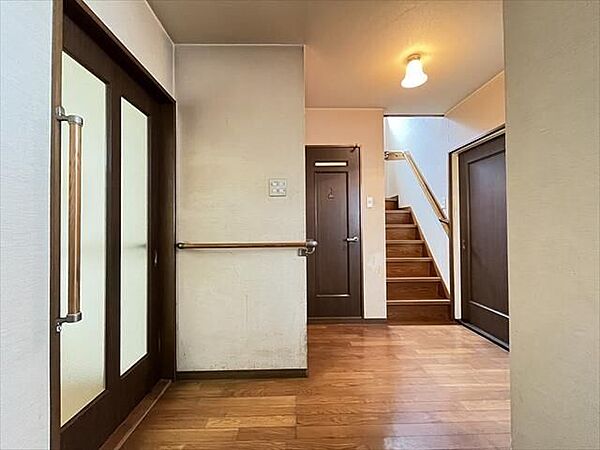 2階：上質な木目調が映える、落ち着きのある広々玄関ホール。手すり付きで将来も安心の設計。