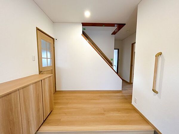 【リフォーム済】玄関から見た廊下の写真です。床はフローリングの重ね張り、クロスの張替えを行いました。手すりも設置しております。