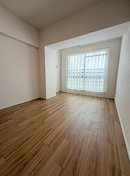 木目調のフローリングが温かみを添えるリビングルーム。家具の配置がしやすいシンプルな空間で、多様なライフスタイルに対応します。