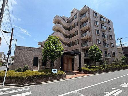 落ち着いた色合いの外観が魅力のマンション。緑豊かな植栽が配され、穏やかな住環境を演出します。