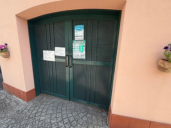 落ち着いた色の壁に、重厚感のあるダークグリーンの扉が印象的。日々の暮らしを彩る植栽も配され、温かみのあるエントランスです。