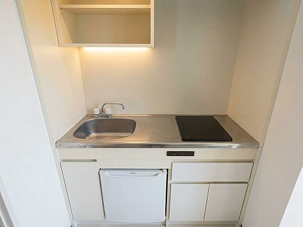 コンパクトながらも調理器具を配置し、効率的な作業スペースを確保したキッチンです。上部収納とシンク下の冷蔵庫で空間を有効活用。