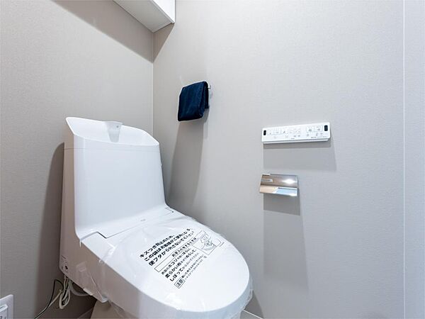【トイレ】いつでも爽やかな使い心地の温水洗浄機能付きトイレ。上部には吊戸棚付きで、トイレットペーパーや清掃用品を収納可能です。