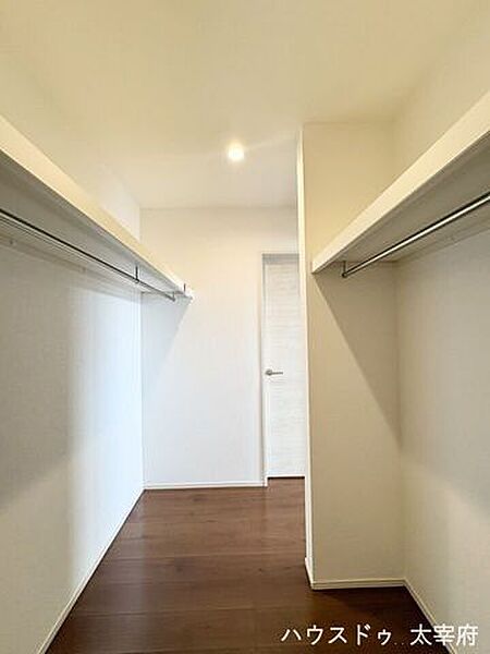【洋室(1)WIC】左右両側にハンガーパイプと上段の棚を備えた、収納力豊富のウォークインクローゼットです。夫婦や家族の衣類を分けてたっぷり収納でき、すっきりと整理整頓できます