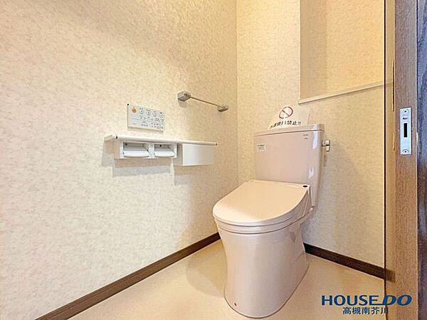 清潔感あふれる温水洗浄便座付きのトイレ。背面にはトイレットペーパーなどを隠して収納できる便利な戸棚を完備。手すりも設置されており安心です。