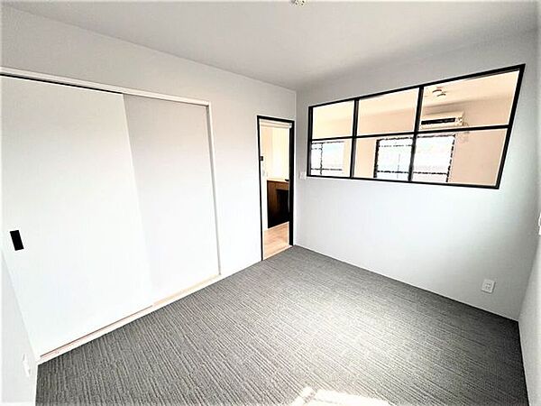 デコマドが解放感をもたらしリビングの光を共有できる寝室。横に大容量クローゼットがあるので室内をすっきり保てます。シックな床色と黒のアクセントが落ち着きあるモダンなプライベート空間を作り出しています。