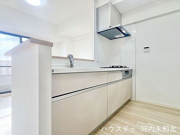 バルコニーからの光が届く、明るい調理スペース。三口コンロ付きで、毎日の料理がスムーズに捗ります。
