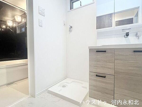 洗濯機置場と洗面台が隣接し、家事効率の良い配置。白を基調とした明るい洗面室です。