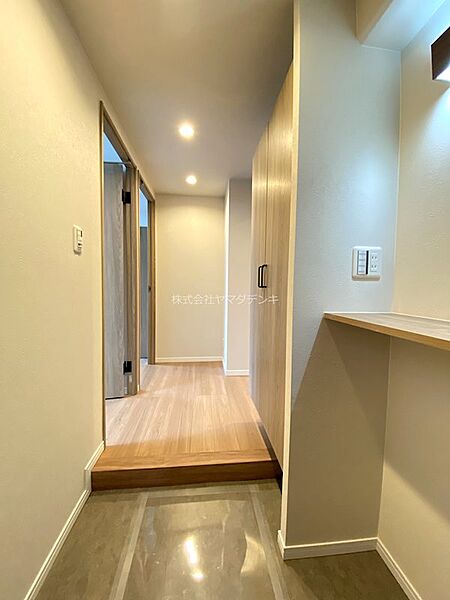 明るい色合いの木目が温かい印象を与える玄関です。天井のダウンライトが足元を優しく照らし、お出迎えを彩ります。