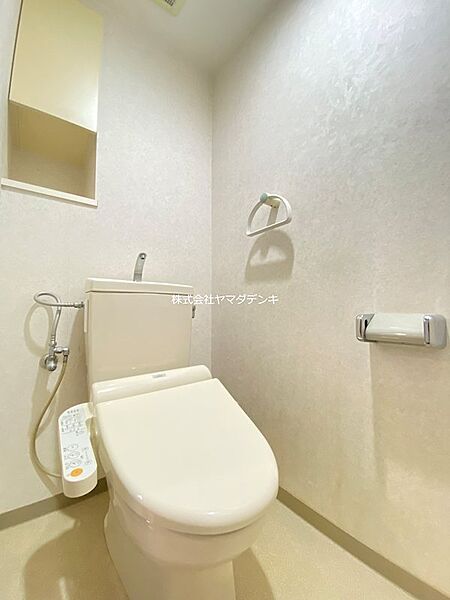 温水洗浄便座付きのトイレは、日々の快適さをサポートします。上部には収納棚も設置され、空間を有効活用できます。清潔感あふれる明るい空間です。