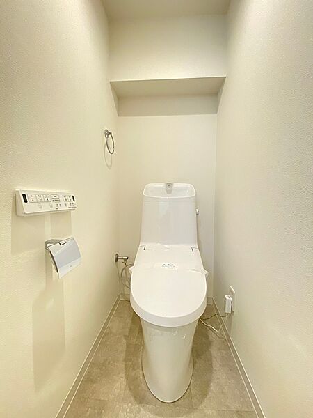 清潔感あふれるトイレは、日々の暮らしに心地よさをもたらします。上部には便利な収納棚を設け、機能性と空間の有効活用を両立しました。