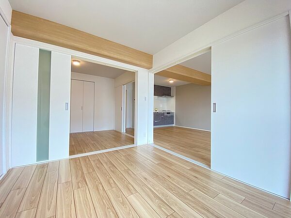 木目調のフローリングが温かみを感じさせる室内。隣接する部屋は引き戸で仕切られ、ライフスタイルに合わせて間取りの変更が可能です。