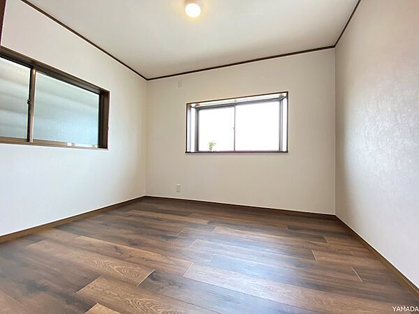 二面に窓を配した、明るく風通しの良好な居室。深みのあるフローリングが落ち着いた空間を演出します。