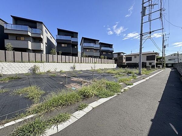 背後には綺麗に整地された擁壁とモダンな住宅街、整然とした道路環境