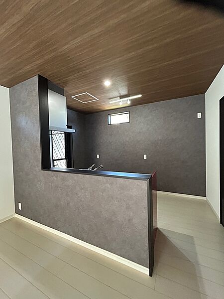 木目調の天井とグレーのアクセントクロスが落ち着いた雰囲気を醸し出すキッチン。料理の時間を豊かに彩ります。