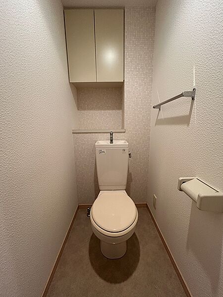 清潔感のあるトイレは、上部収納と手洗い付きで機能的。壁紙のデザインが空間にアクセントを添えます。