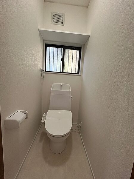 清潔感のあるシンプルなデザインのトイレです。換気窓と換気扇で、いつも快適な空間を保てます。収納棚も備わり、機能性にも配慮しています。