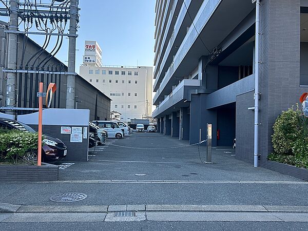 ゲート付き駐車場から奥へ進むと、洗練されたデザインのマンションが見えます。周辺には商業施設もあり、生活の利便性がうかがえます。